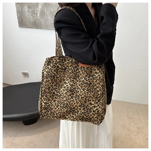 Detail shot of leopard print canvas tote bag with side pocket and brown leather brand label