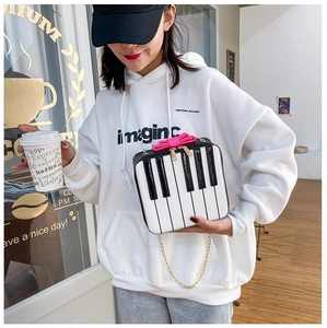Detail of piano keyboard style crossbody bag with pink bow and gold chain strap