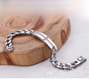 Macro shot of silver Cuban chain bracelet with a sparkling diamond-set cross centerpiece