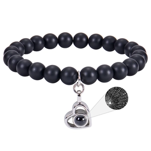 Detail of heart pendant with 100 languages projection stone on black bead bracelet