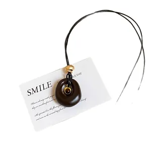 Collier avec pendentif ovale en résine oeil de tigre et perles dorées sur carte minimaliste