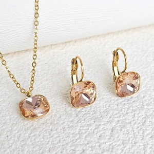 Macro shot of gold-plated stainless steel necklace and earrings with peach zircon gems