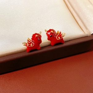 Detail of red enamel unicorn earrings with gold wings on a luxury jewelry box display