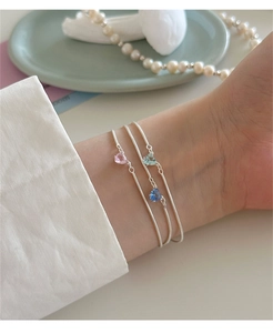 Dettaglio ravvicinato di tre braccialetti in argento 925 con zirconi a forma di cuore