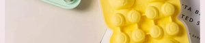 Close-up of yellow and green bear-shaped silicone ice cube molds on a clean surface