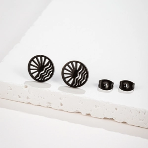 Detail of round black matte stud earrings with hollow sunburst pattern on stone base