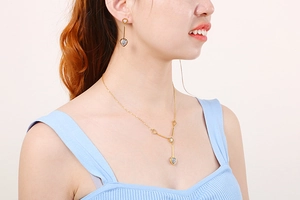Close-up of gold heart necklace and earrings with black and white striped pattern details