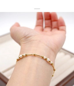 Close-up of minimalist pearl and gold bead bracelet on wrist with elegant texture