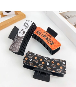 Detailed view of Halloween hair claws featuring pumpkin and ghost motifs on a book