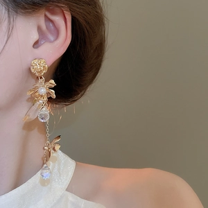 Detail of elegant gold flower tassel earrings with pearls and crystals on a model