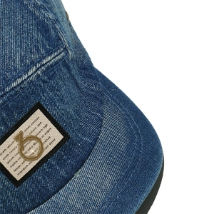 Detailed view of a washed blue denim baseball cap featuring a vintage label and metal ring