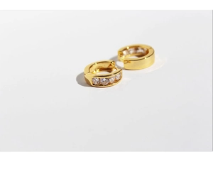 Detail of gold huggie hoop earrings with channel-set white cubic zirconia stones