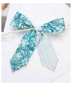 Close-up of blue floral skinny silk scarf tied as a bow on a wooden bar detail