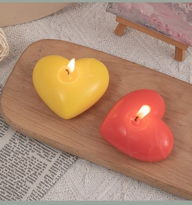 Close-up of red and yellow heart-shaped woven scented candles on a wooden tray