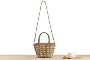 Detail of handwoven large capacity straw tote bag with green handles and strap