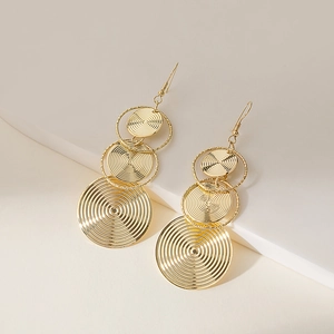 Detailed close-up of golden tiered circular drop earrings with textured concentric patterns