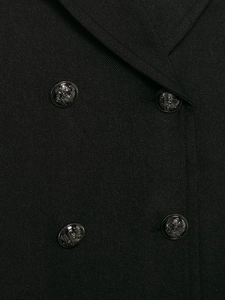 Close-up of embossed metal buttons on a black wool blend coat with twill texture