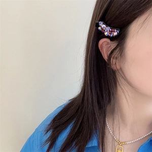 Détail d'une pince à cheveux en cristal coloré portée sur le côté des cheveux