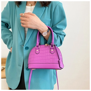 Close-up of purple shell bag with crocodile texture and gold hardware on model