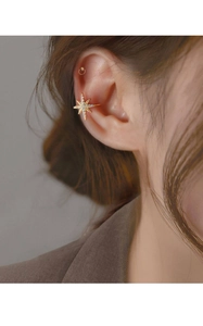 Macro detail of star-shaped gold ear cuff with zircons worn on a model's ear