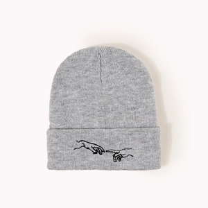Détail de la broderie de deux mains sur le revers d'un bonnet en maille gris