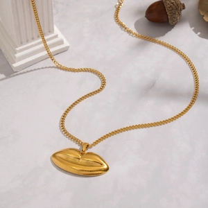 Detailed view of a gold lip-shaped pendant necklace on a decorative marble surface