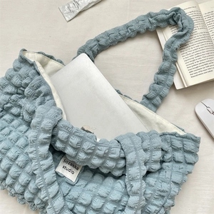 Detailed top view of blue popcorn texture tote bag with laptop and office essentials
