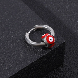 Silver stainless steel hoop earrings with red evil eye bead on a textured surface