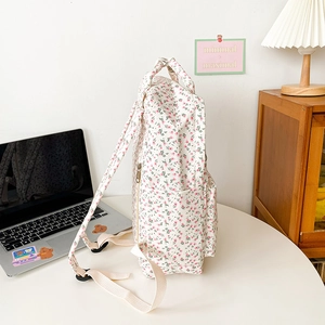 Close-up of floral canvas backpack side pocket with metal zipper and reinforced strap