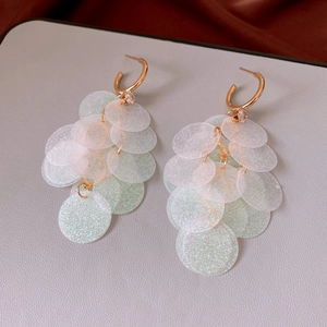 Close-up of golden C-shaped earrings with shimmering pearlescent sequin tassels