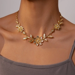 Close-up of gold flower leaf necklace with rhinestones worn on a model neckline