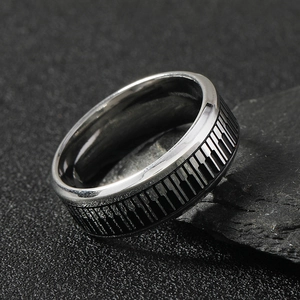 Modern stainless steel piano key ring displayed on natural black sand and stone scenery