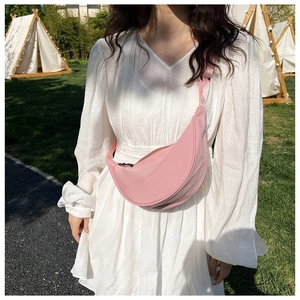 Close-up of pink nylon crescent bag with adjustable strap worn by model in outdoor setting