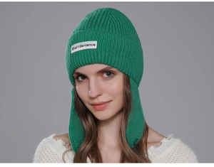 Detail of bright green ribbed knit beanie with ear protection and brand label