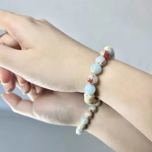 Detail of a handmade natural stone bead bracelet with colorful quartz on a woman's wrist
