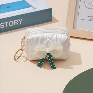 Detail of white quilted mini pouch with pearl mesh bow and golden keychain ring