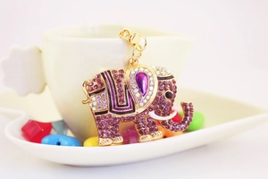 Détail macro d'un porte-clés éléphant avec cristaux violets sur une soucoupe blanche