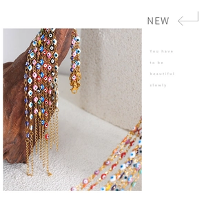 Detail view of colorful evil eye charms on a gold chain draped over a wooden decor