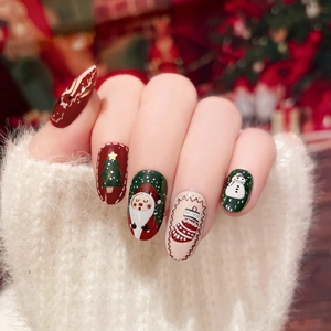 Christmas press-on nails with reindeer, Santa, and tree designs on festive red and green