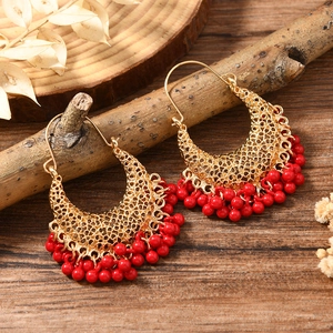Vue détaillée de boucles d'oreilles bohèmes croissant doré avec pompons perles rouges