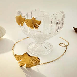 18K gold ginkgo leaf jewelry set with necklace and earrings displayed on a glass