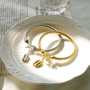 Detailed shot of gold and silver twisted bangles with shell charms on a ceramic plate