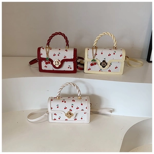 Close-up of square crossbody bags with cherry prints, floral buckles, and braided handles