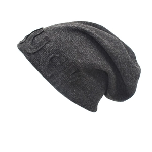 Detail of dark grey knitted beanie featuring 3D embossed letter and cozy ribbed texture