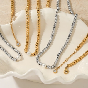 Minimalist beaded pearl necklaces in gold and silver finish on a shell tray