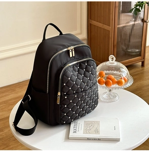 Dettaglio zaino in nylon trapuntato nero con decorazioni di perle e cerniere dorate