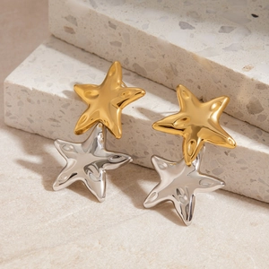 Star shaped 18K gold and silver stainless steel earrings on a stone surface