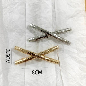 Detail view of X-shaped alloy hair clip with hammered metal texture and size markings