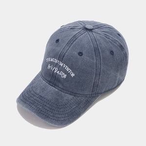 Detail of white embroidery text on washed navy blue cotton twill baseball cap