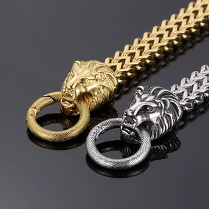 Macro detail of lion head charm with heavy industrial woven chain in gold and silver finish